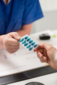 Close-up of female veterinarian giving pills blister to pet owner's hand