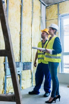 Construction manager and architect checking the insulation works in a half finished project