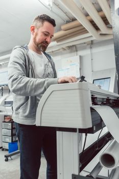 Man preparing large format printer for a banner print job on vinyl
