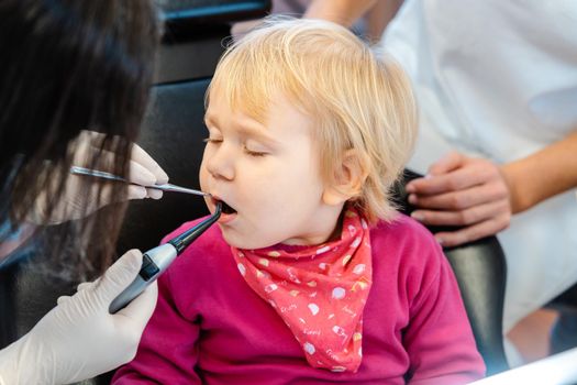 Woman dentist looking after baby teeth of a little girl in her surgery