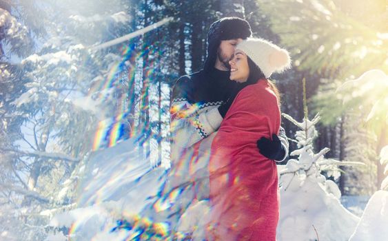 Romantic couple keeping each other warm on winter hike in the woods full of snow