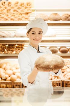 Beautiful woman selling bread in bakery offering a loaf