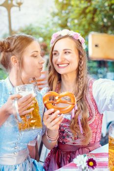 Best friends in Bavarian Tracht making a Selfie with the phone, beer, and a pretzel