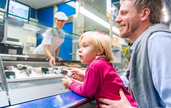 Family at the fish counter in a supermarket looking at what is on offer