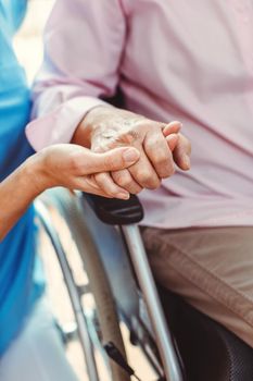 Nurse consoling a senior woman in the nursing home holding her hand in the nursing home