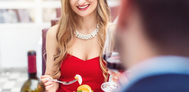 Couple toasting with red wine in romantic restaurant looking at each other