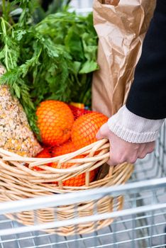 Woman getting her shopping basket full with groceries out of the cart