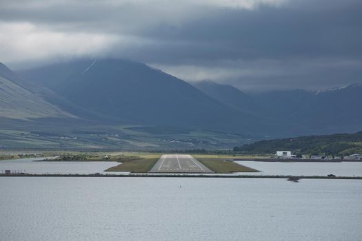 View from the end of runway at Akureyri airport in Iceland. A small plane is taking off.