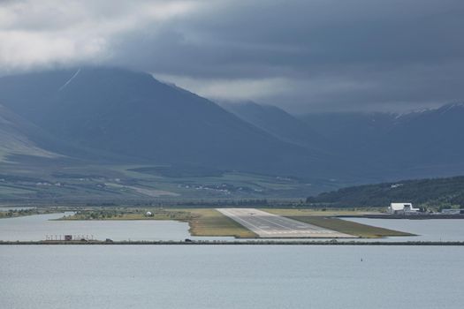View from the end of runway at Akureyri airport in Iceland. A small plane is taking off.