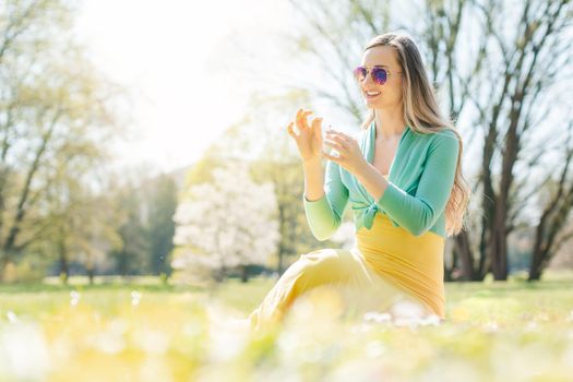 Beautiful woman sitting on a spring meadow picking daisy flower to find out if he loves her