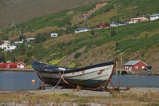 Old vintage boat with a small town of Eskifjodur located in east Iceland in the background.