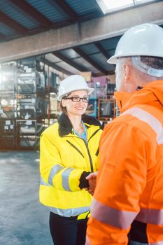 worker and customer in logistics warehouse having handshake to seal a deal