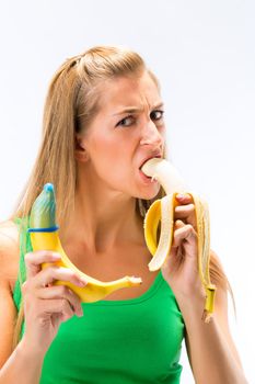 Portrait of young woman eating banana and showing other banana having condom