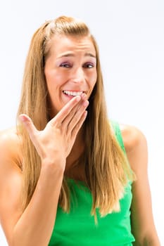 Close-up of blonde young woman laughing with hand over the mouth isolated over white background