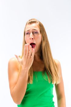 Portrait of sleepy young woman yawning against white background