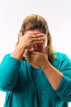 Close-up of fatty woman covering her face with two hands against white background