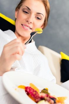 Happy young woman eating healthy food in breakfast