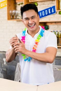 Close-up of smiling male bartender shaking cocktail in bar