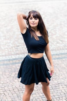 Portrait of an stylish young woman with hand behind her head standing on pavement