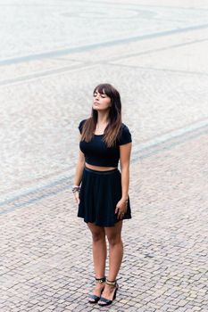 Portrait of pretty young woman with eye closed standing on pavement