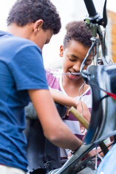 Close-up of two boys repairing an old bike