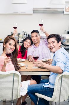 Group of smiling friends enjoying the red wine at home