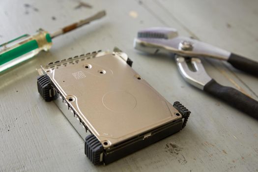 Broken and Destroyed Hard Drive Disk and Tools on Wooden Table.