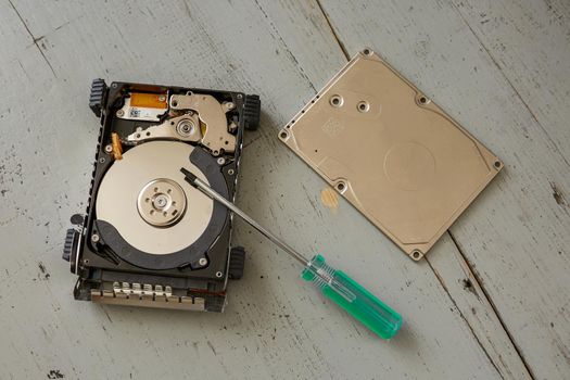 Broken and Destroyed Hard Drive Disk and Tools on Wooden Table.