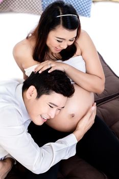 Overhead view of smiling man listening to his pregnant wife's belly