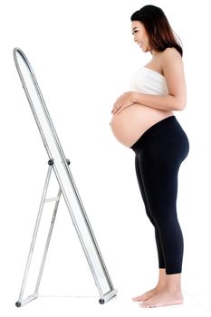 Side view of smiling pregnant woman looking at mirror against white background