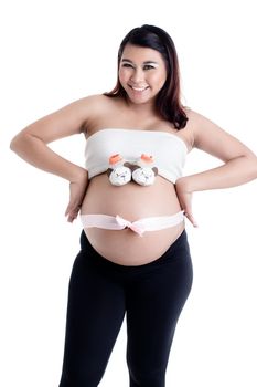 Smiling pregnant woman's belly with baby shoes and ribbon bow against white background