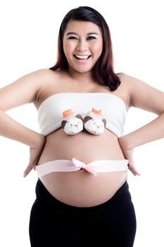 Pair of baby shoes over the smiling pregnant woman's belly with pink satin ribbon bow