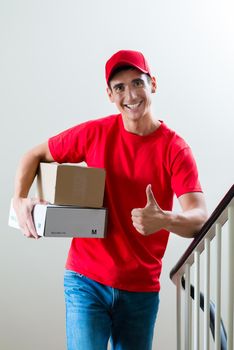 Portrait of smiling delivery man holding mail boxes showing thumbsup sign