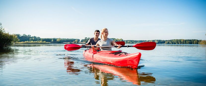 Portrait of happy couple enjoying the kayaking on idyllic lake