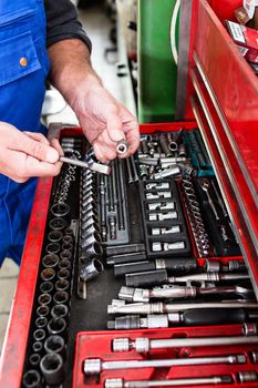 Mechanic man holding tool for repair and diagnostics of cars in the garage