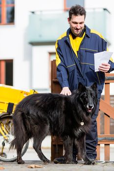 Big black dog welcoming cheerful postman at garden gate