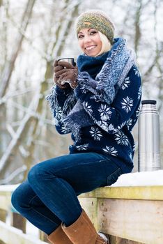 Woman freezing on a cold winter day warming herself up with hot drink in the snow