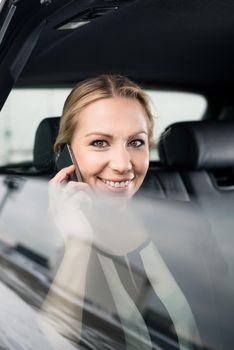 Happy businesswoman travelling in car talking on cellphone