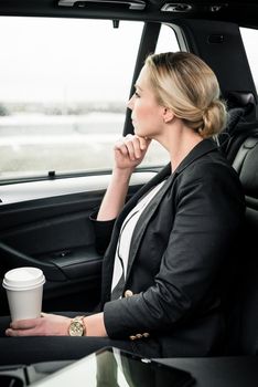 Close-up of contemplated businesswoman holding coffee cup sitting in the car