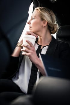 Close-up of young businesswoman holding takeaway coffee cup in car