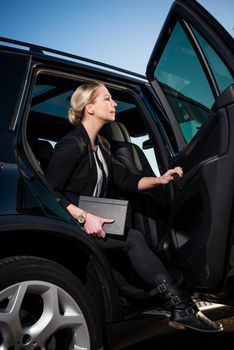 Businesswoman in suit holding diary alighting from car