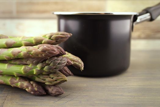Fresh green asparagus spears near black metal pot in close up conceptual of gourmet eating in spring