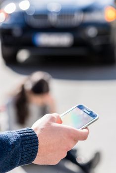 Close-up of the hand of a man calling the emergency number for helping an injured woman after bicycle accident on the street