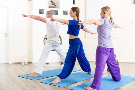 Healthy people performing stretching exercise in yoga class