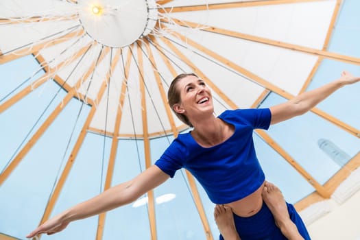 Close-up of smiling fit woman balancing on man's feet