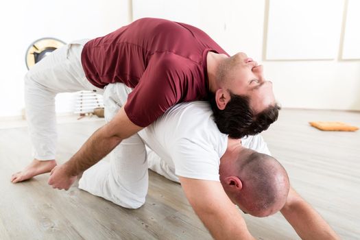 Man relaxing on his partner's back while doing acroyoga