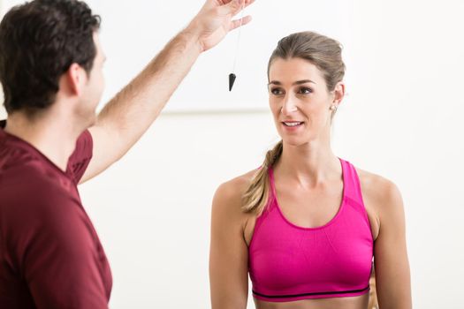 Male instructor sitting on ground hypnotizing fit young female