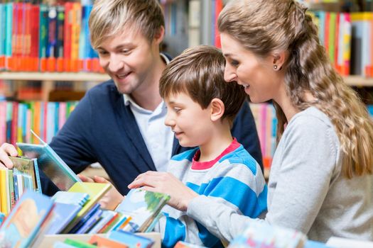 Family reading a book in the library, mother, father and son