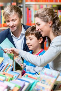 Family reading a book in the library, mother, father and son