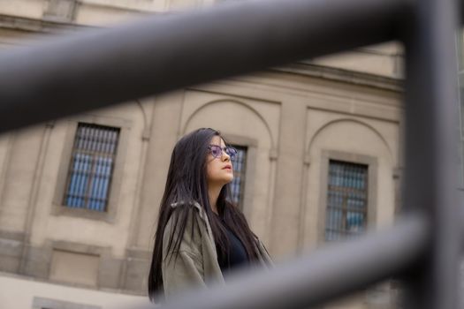 Young girl seen between two railings with a building in the background.